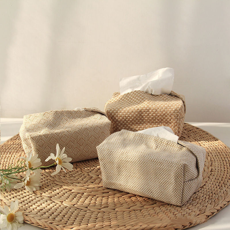 Three woven tissue boxes on a woven mat with white flowers.